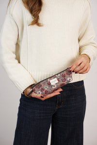 Woman holding DE LA MUR burgundy and gray floral pencil case, lifestyle shot