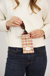 Model slipping sunglasses into the DE LA MUR gingham jacquard glasses case
