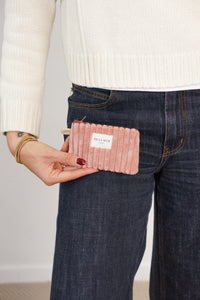 Model holding DE LA MUR dusty rose corduroy coin purse at hip, lifestyle shot