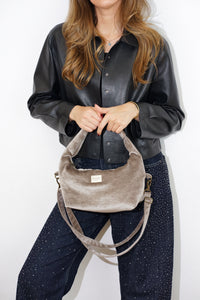 Model holding the DE LA MUR chocolate brown velvet evening bag by the handle