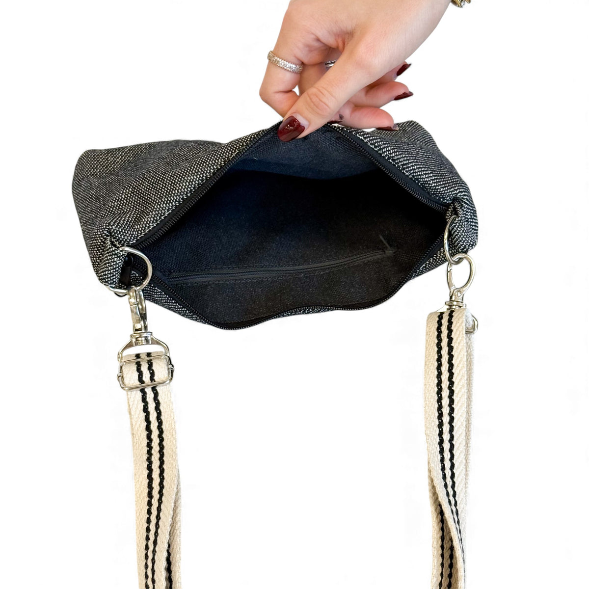 Open DE LA MUR Sinay clutch showing the lined interior and detachable striped strap