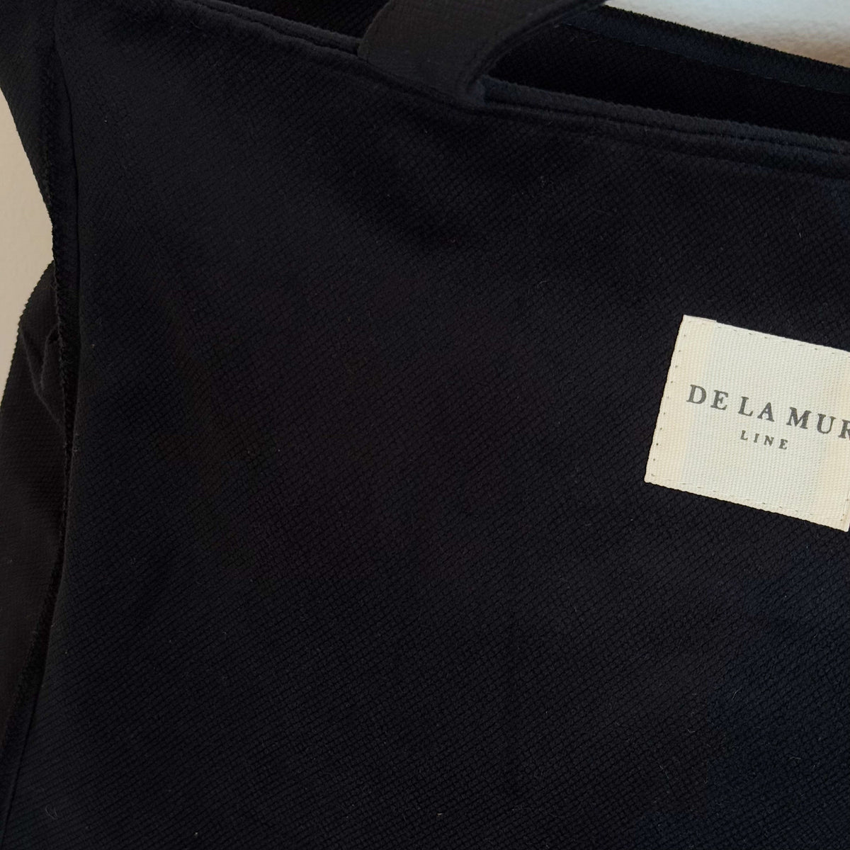 Close-up of the black canvas fabric and DE LA MUR Line woven label