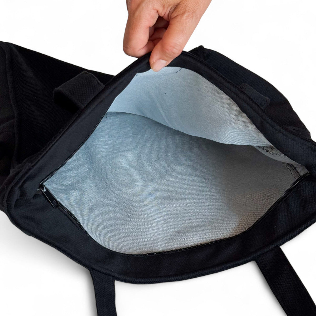 Open DE LA MUR black tote bag showing the light gray lined interior