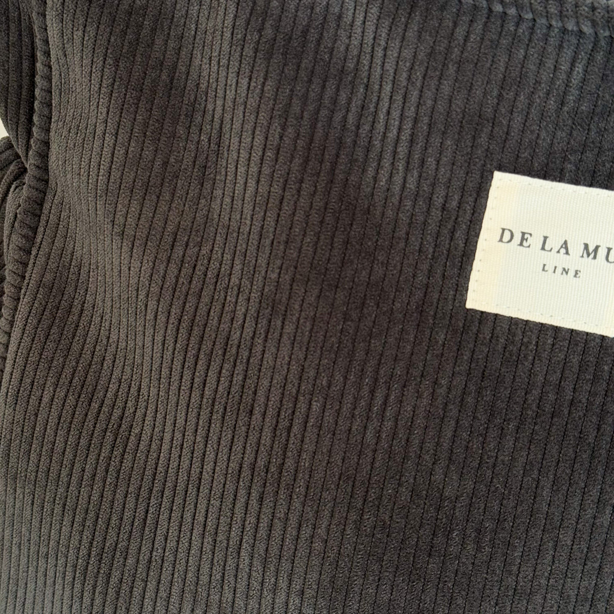 Close-up of the gray corduroy fabric and DE LA MUR Line woven label