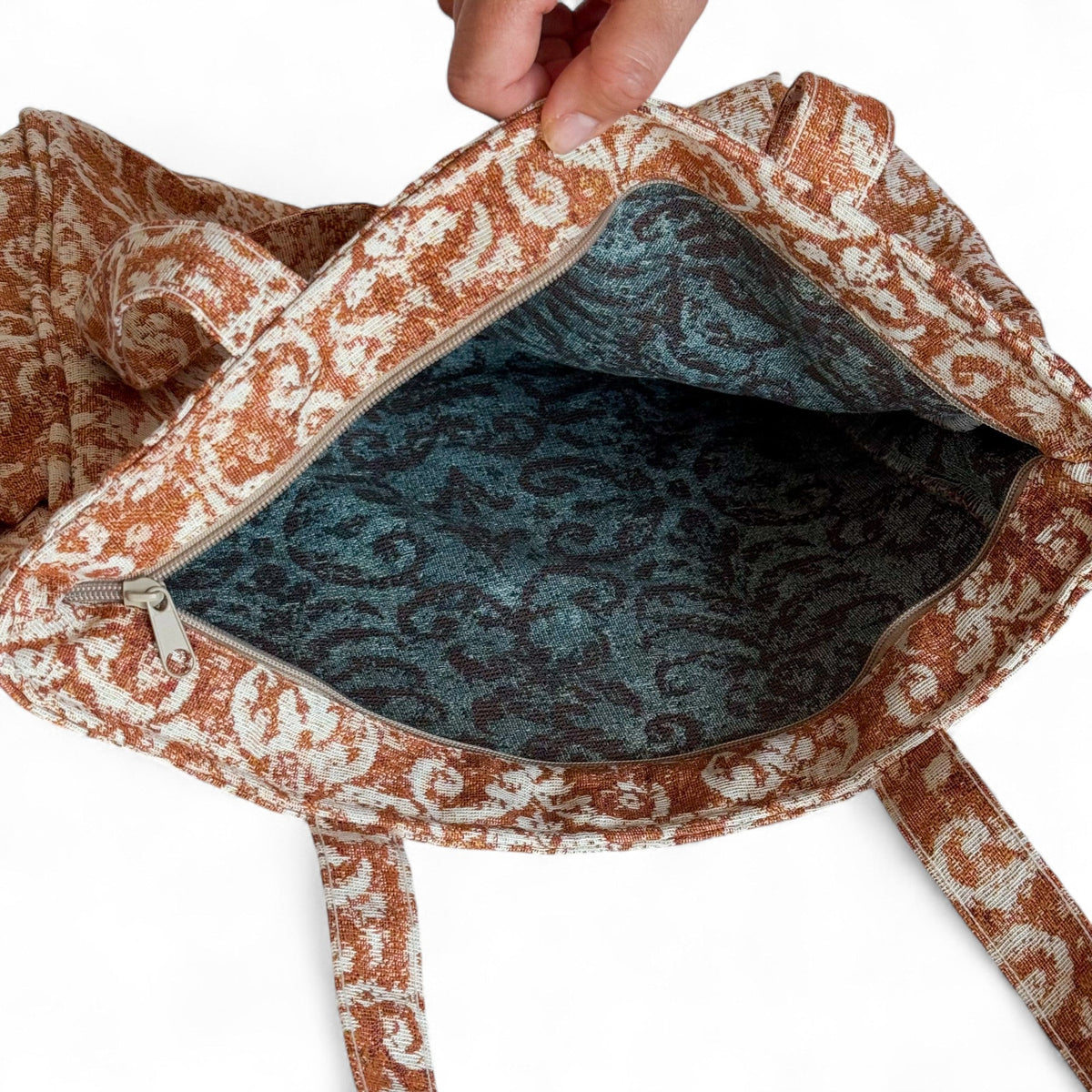Open DE LA MUR rust jacquard tote bag showing the teal patterned interior