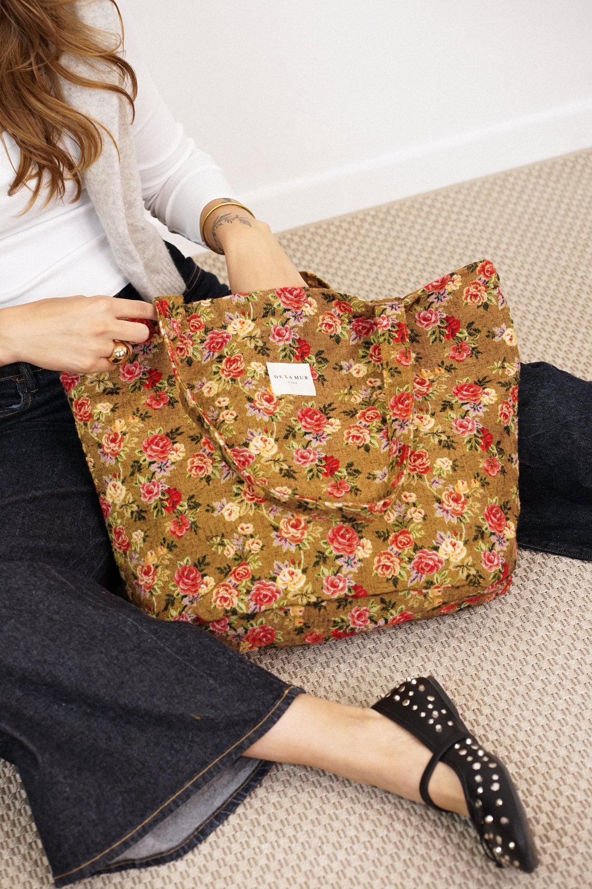 DE LA MUR Esme floral jacquard tote bag resting on model's lap, lifestyle close-up