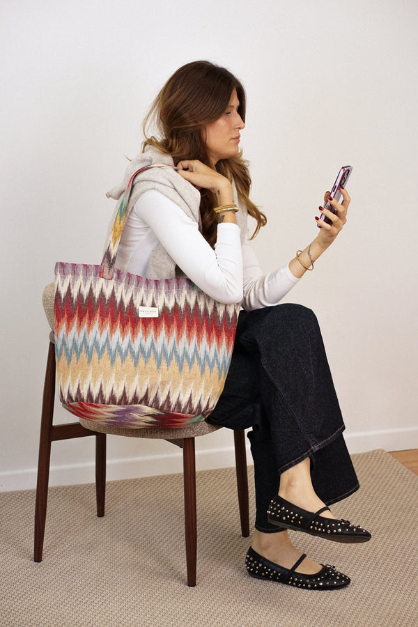 Seated model with the DE LA MUR Guana zigzag jacquard large zippered bag, lifestyle shot