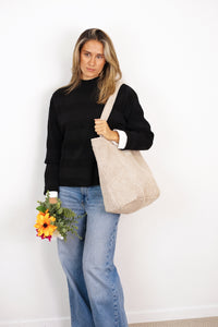 Model carrying DE LA MUR cream beige corduroy large zippered bag, lifestyle shot