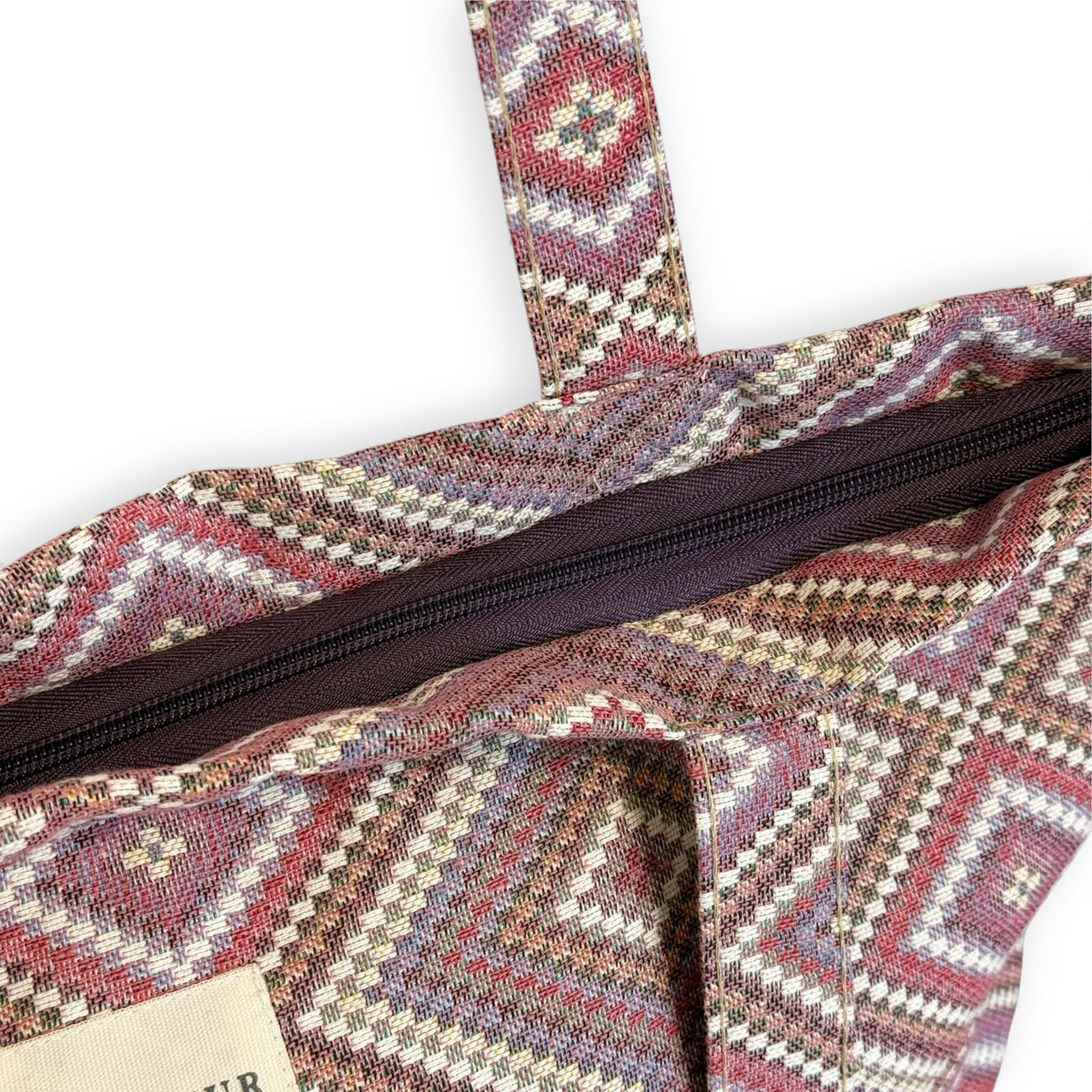 Close-up of the open top zip on the DE LA MUR Nana jacquard tote bag