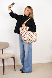 Model with the DE LA MUR geometric jacquard large zippered bag on her shoulder, lifestyle shot