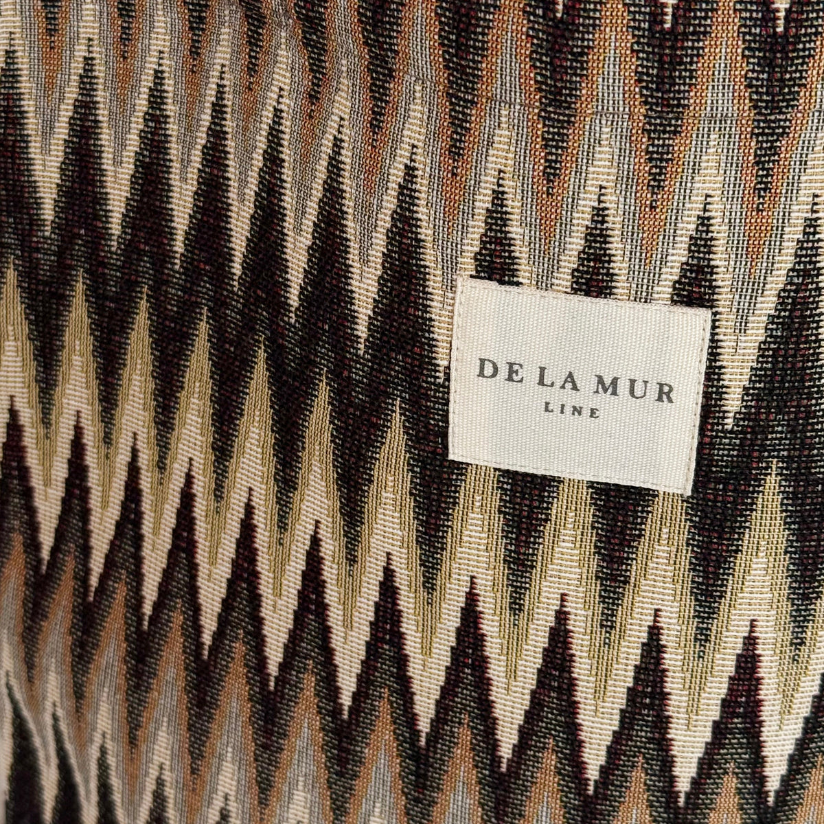 Close-up of the brown zigzag jacquard fabric and DE LA MUR Line label