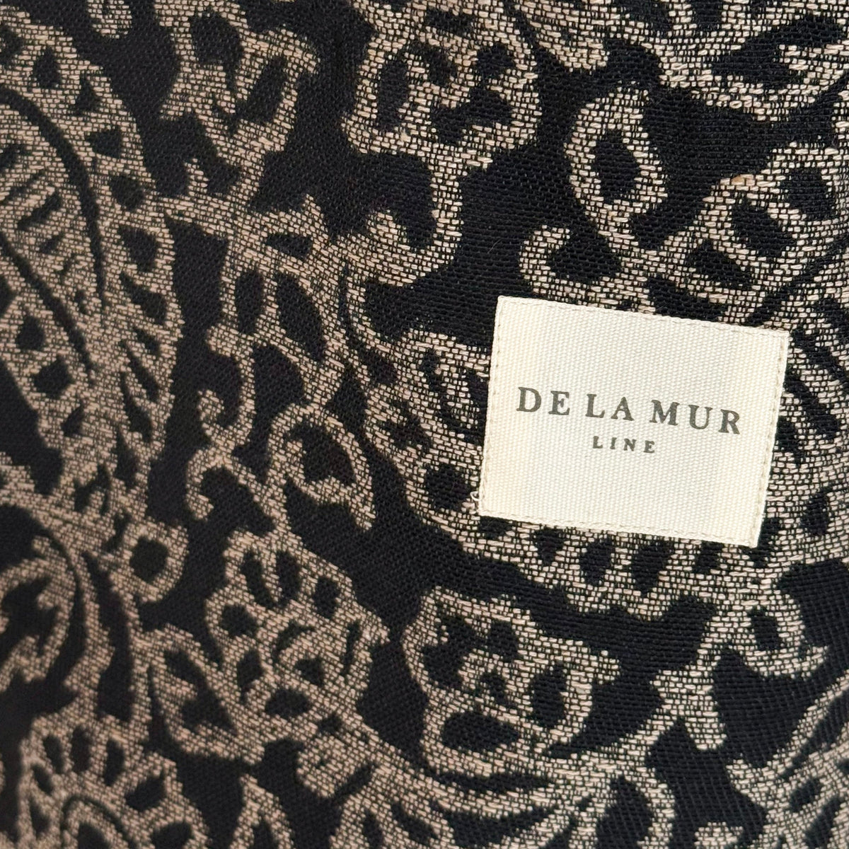 Close-up of the floral paisley jacquard weave and DE LA MUR Line label