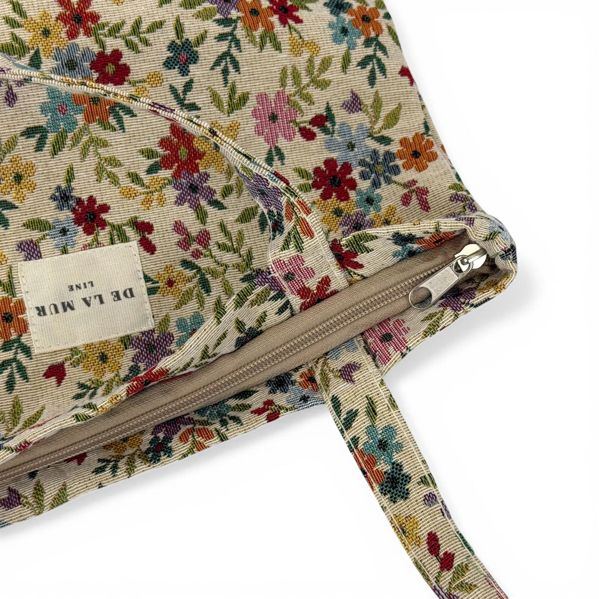 Close-up of DE LA MUR Blum bag zip closure and floral jacquard fabric with Line label