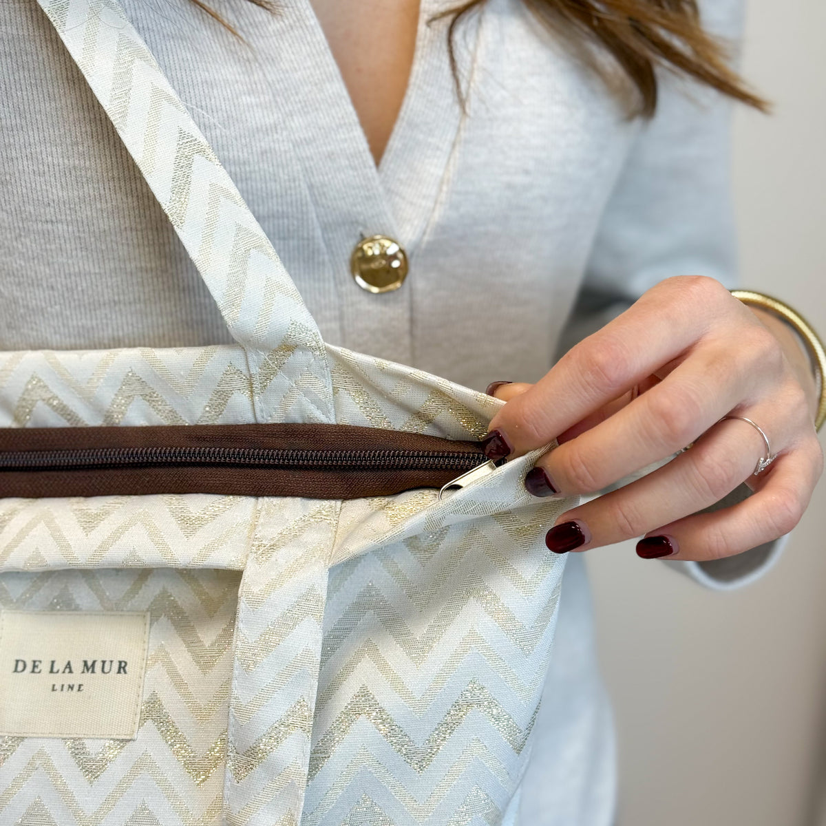 Close-up of the DE LA MUR zigzag bag zip opening, held by a model