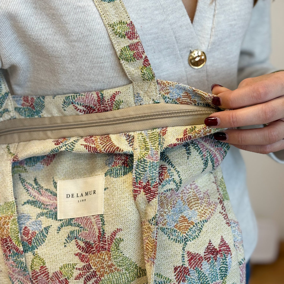 Model opening the DE LA MUR floral bag, showing the lined interior