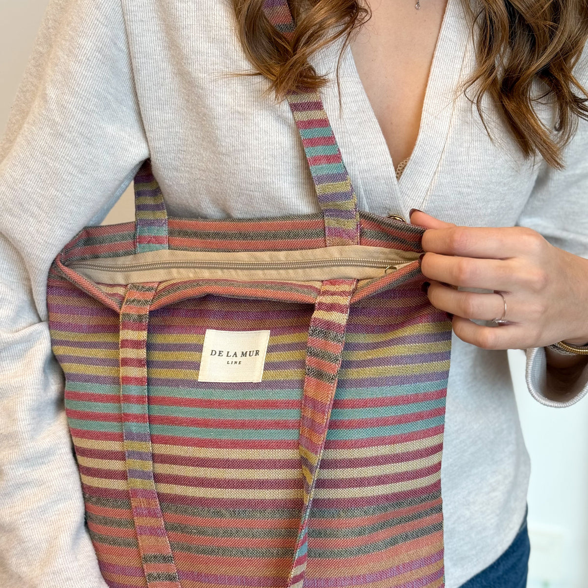 Close-up of model holding the DE LA MUR Maria bag with open zip top