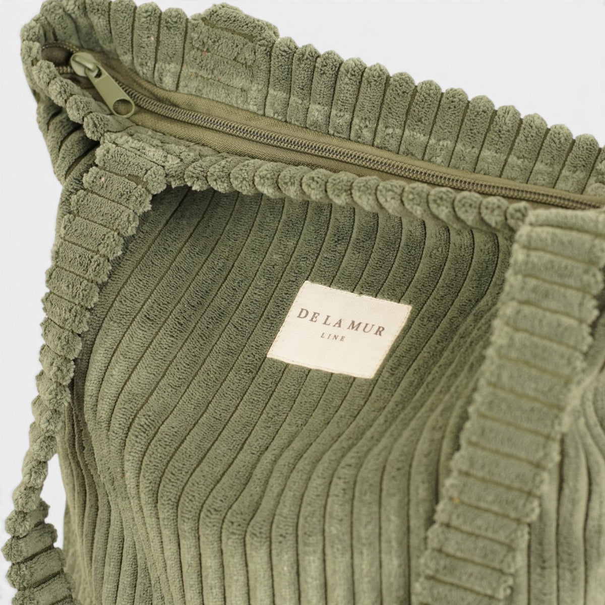 Open DE LA MUR Musgo corduroy bag showing the zip top and lined interior with brand label