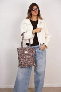 Model carrying DE LA MUR Nira floral jacquard zippered bag on the shoulder, lifestyle shot