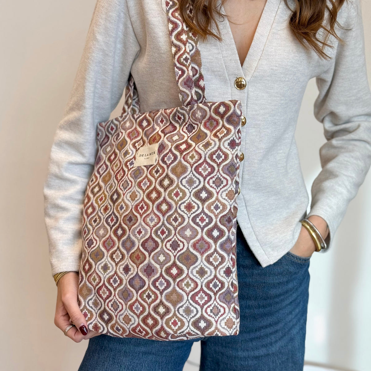 Features infographic of the DE LA MUR Onda geometric jacquard bag with model