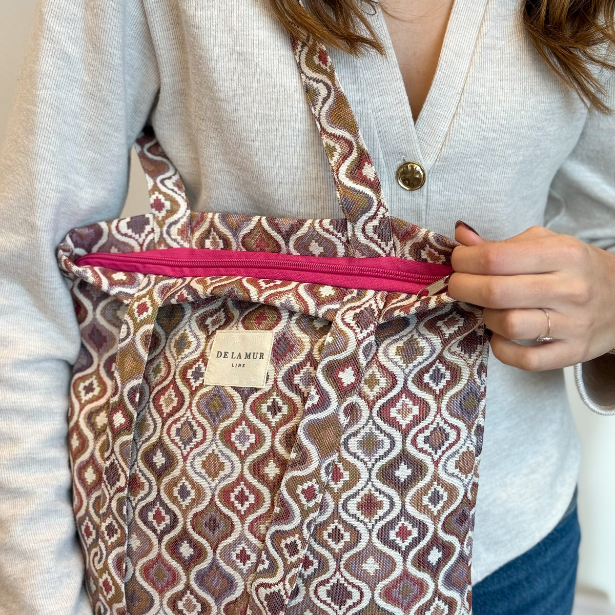 Model opening the zip of the DE LA MUR Onda bag to reveal the interior