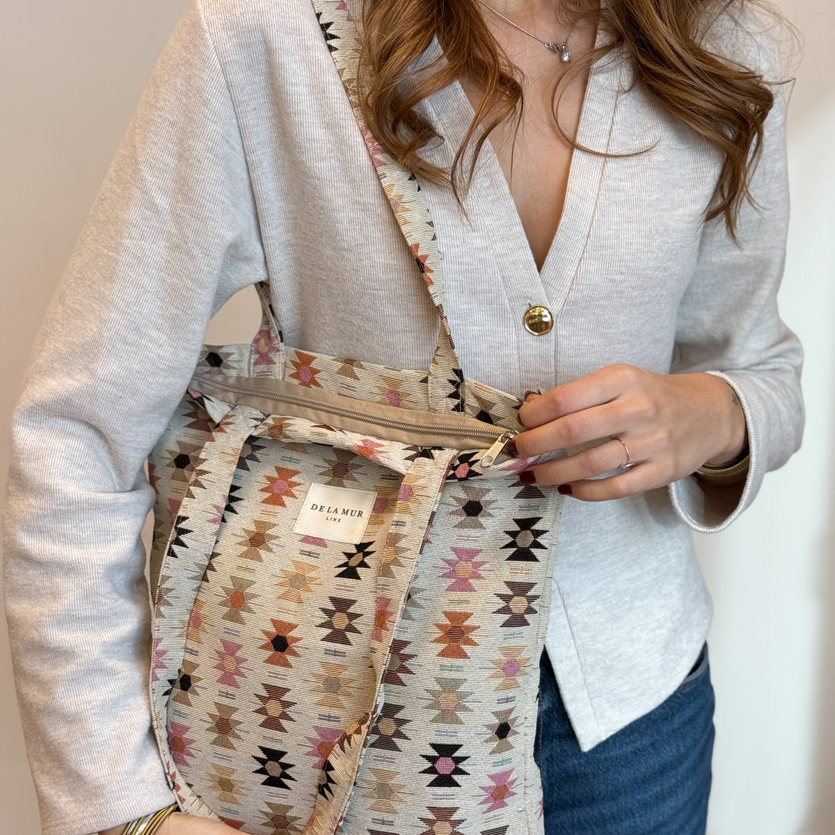 Model opening the zip of the DE LA MUR Royal bag to reveal the interior