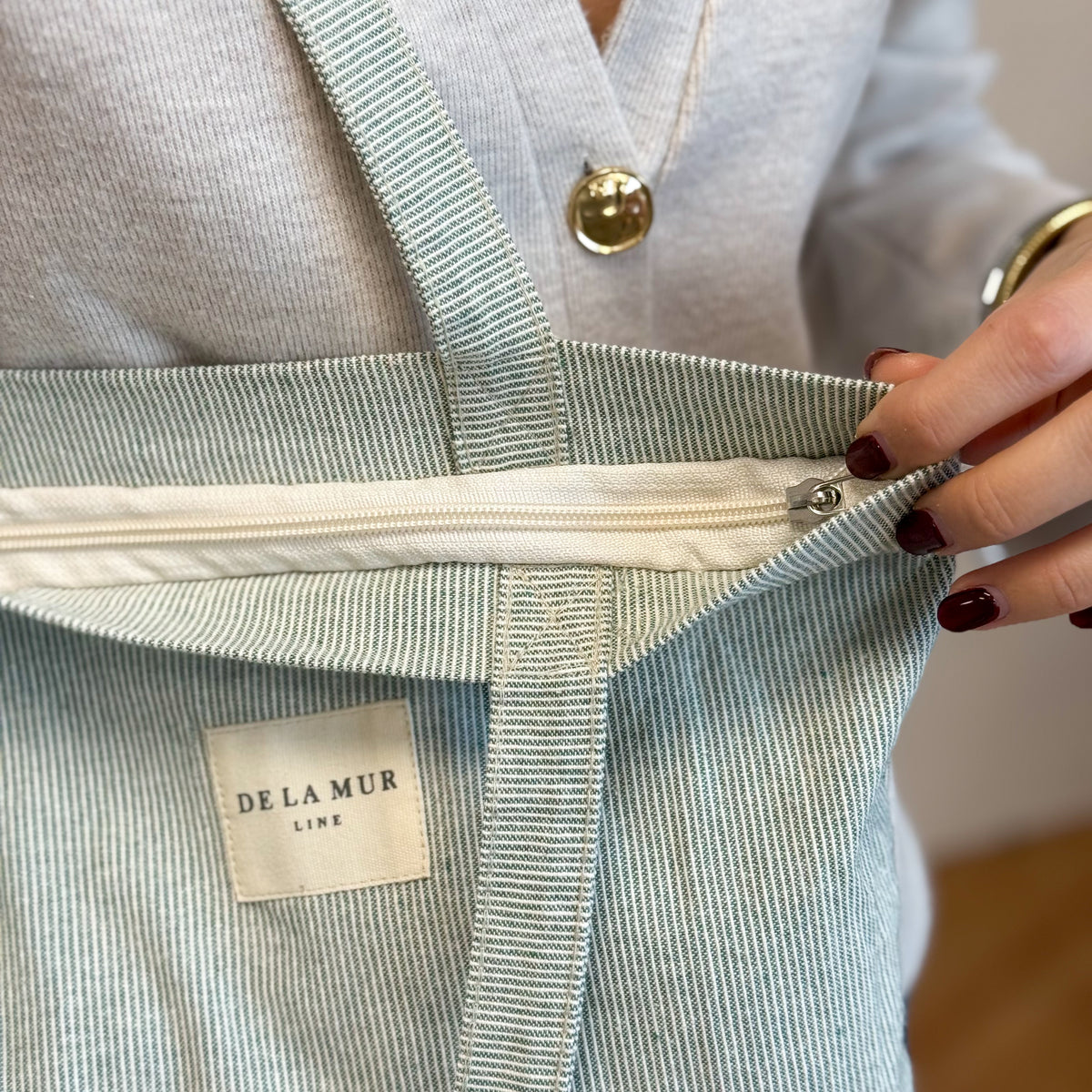 Detail of the DE LA MUR Teo tote zip closure and woven label, held open