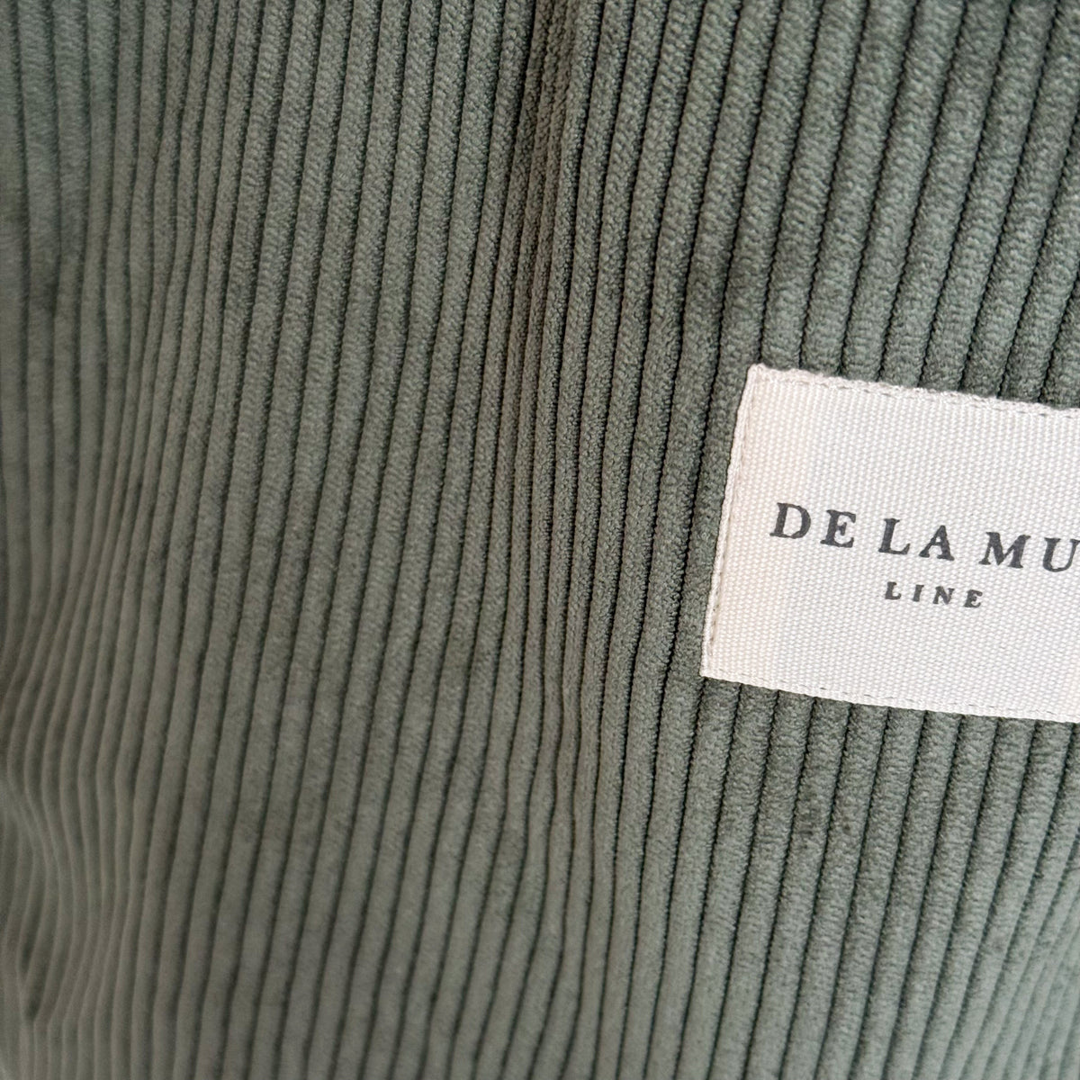 Close-up of the ribbed green corduroy and DE LA MUR Line label on the Tree tote