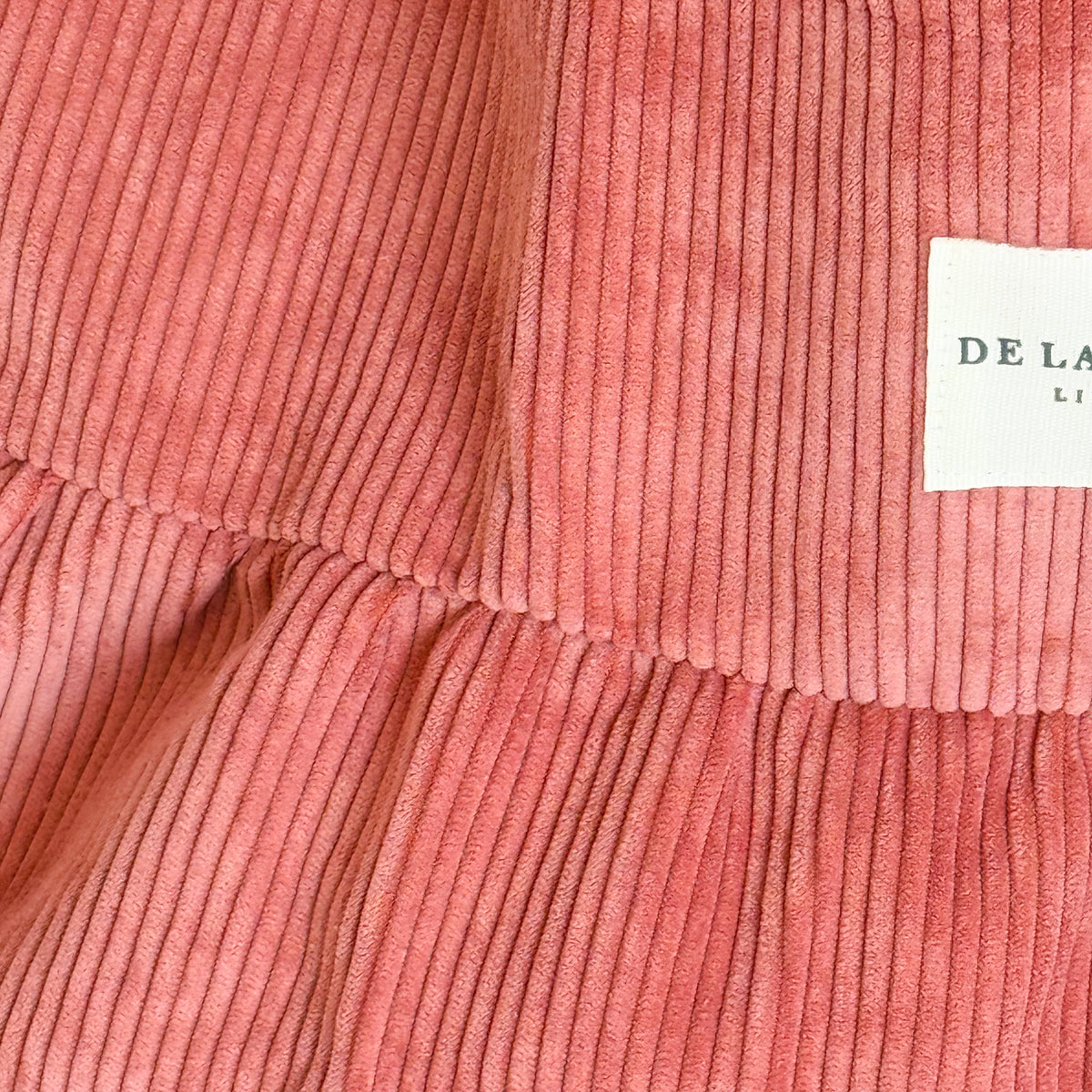 Close-up of the coral corduroy texture and DE LA MUR Line label