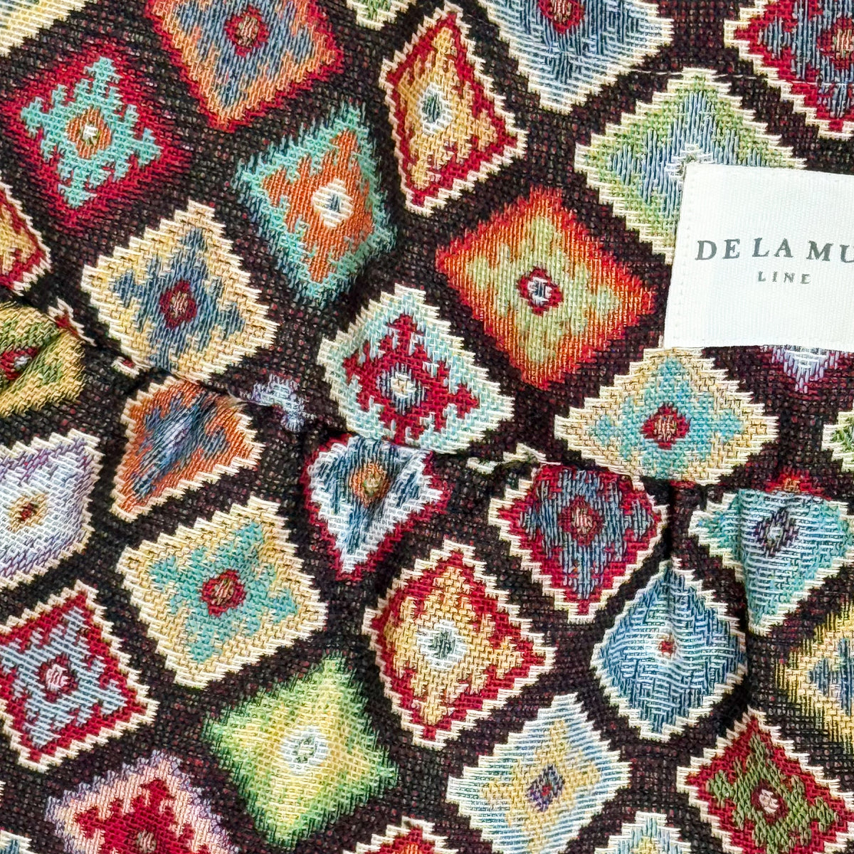Close-up of the multicolor diamond jacquard fabric and DE LA MUR Line label