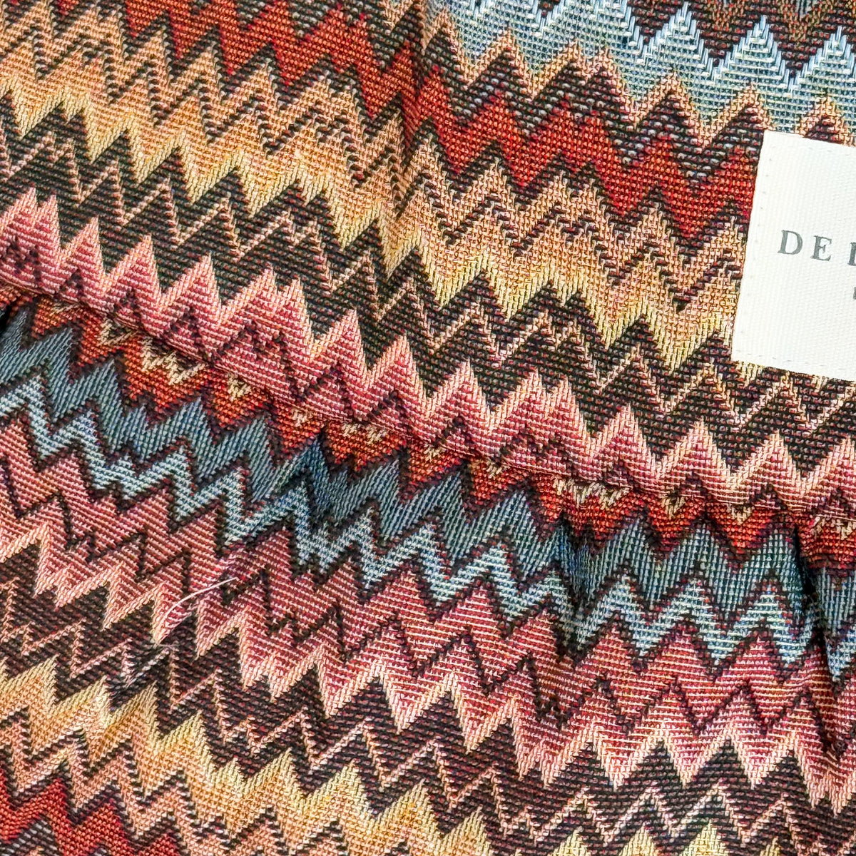 Close-up of the colorful zigzag jacquard fabric and DE LA MUR Line label