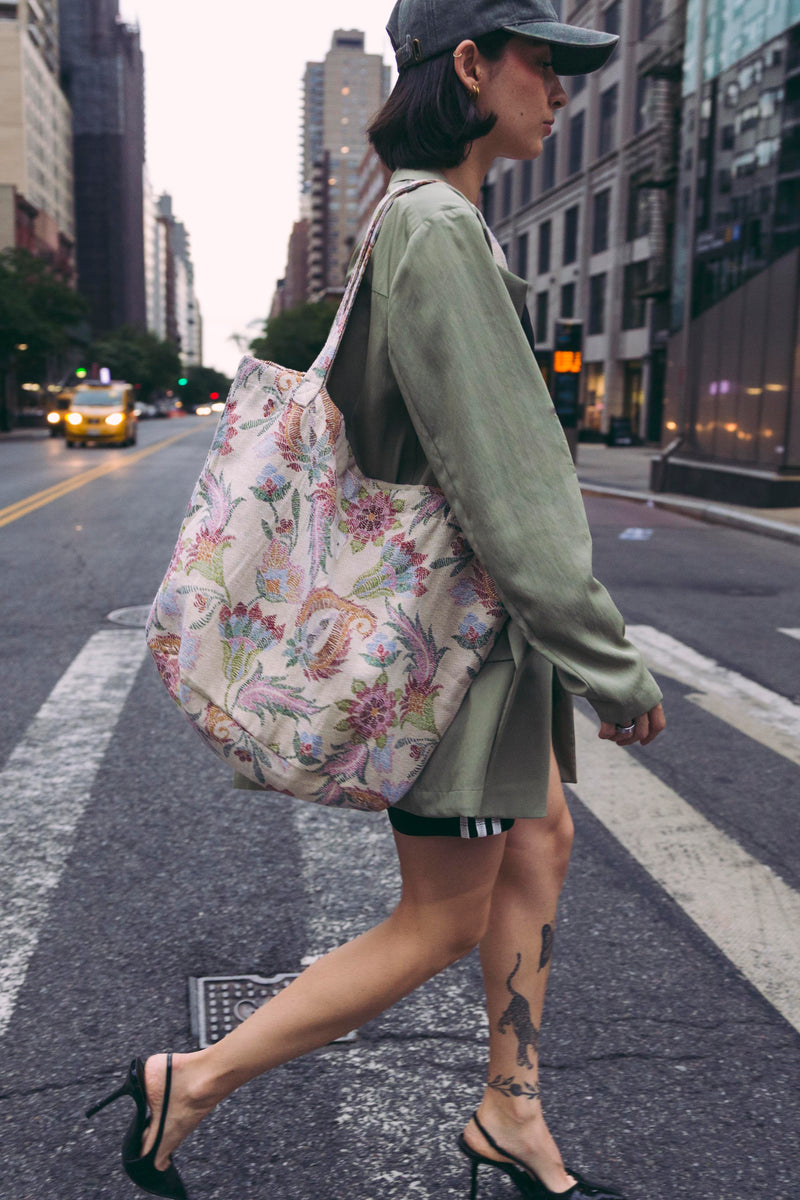 Model crossing a New York street with the DE LA MUR Color floral jacquard large zippered bag