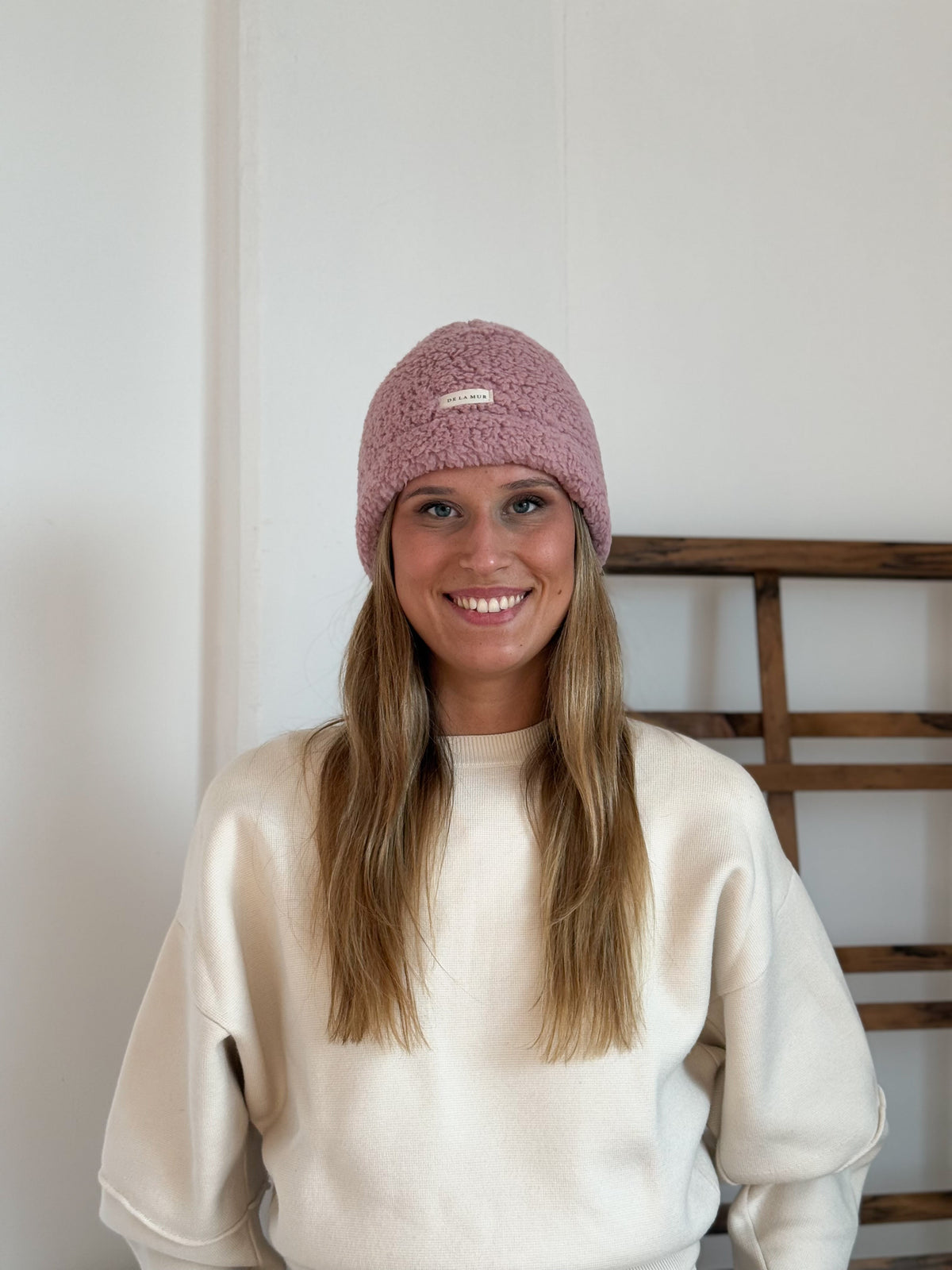 Model wearing the DE LA MUR pink Sherpa Beanie, front view with logo label