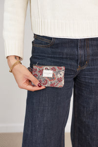Model holding the DE LA MUR burgundy and gray floral jacquard coin purse at her pocket