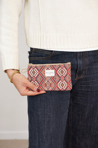Model holding DE LA MUR red multicolor geometric jacquard makeup bag, lifestyle shot