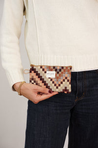 Model holding DE LA MUR brown and beige jacquard coin purse at the hip, lifestyle shot