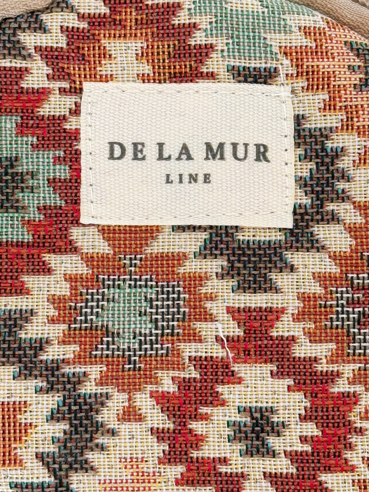 Close-up of the multicolor geometric jacquard fabric and DE LA MUR Line label