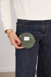 Model holding DE LA MUR olive green corduroy round coin purse at jeans pocket, lifestyle shot