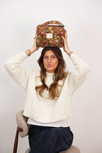 Woman holding the DE LA MUR Esme floral rose jacquard makeup bag, lifestyle shot