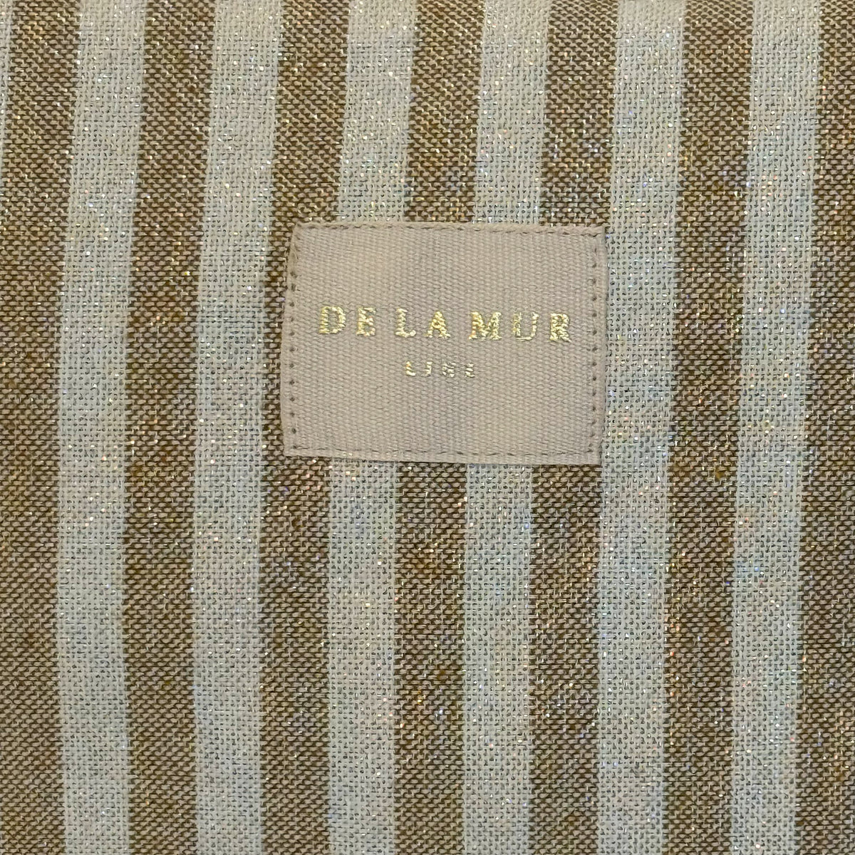 Close-up of beige striped fabric and DE LA MUR Line label on the Lumos bag