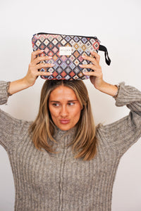 Woman holding the multicolor geometric DE LA MUR makeup bag above her head