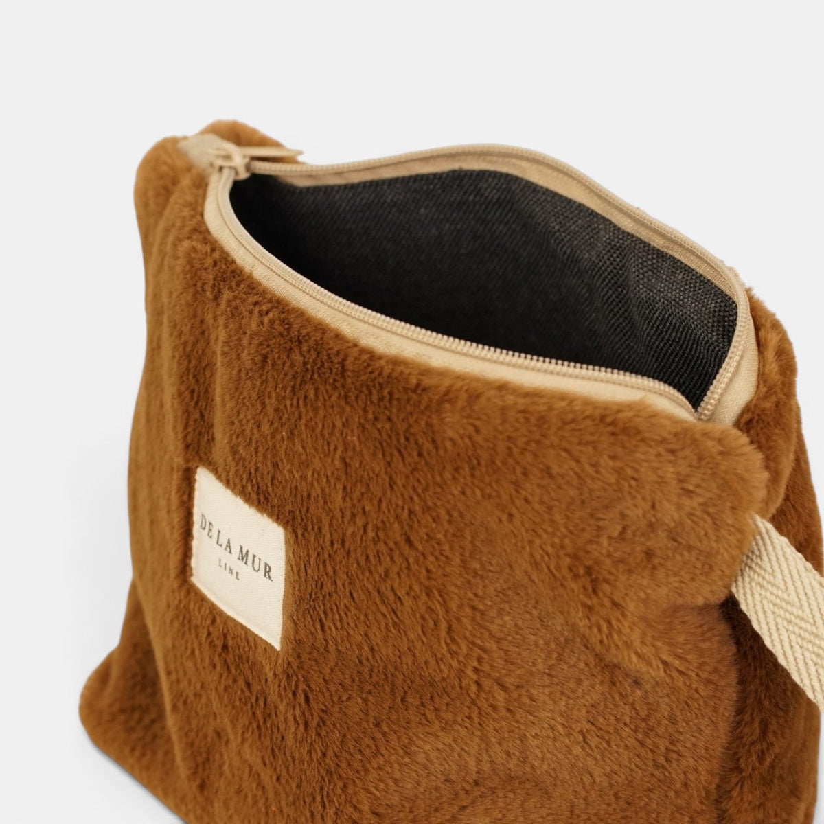 Open DE LA MUR camel faux fur makeup bag showing the dark lined interior