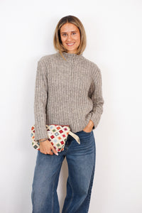 Model holding the DE LA MUR multicolor geometric jacquard makeup bag, lifestyle shot