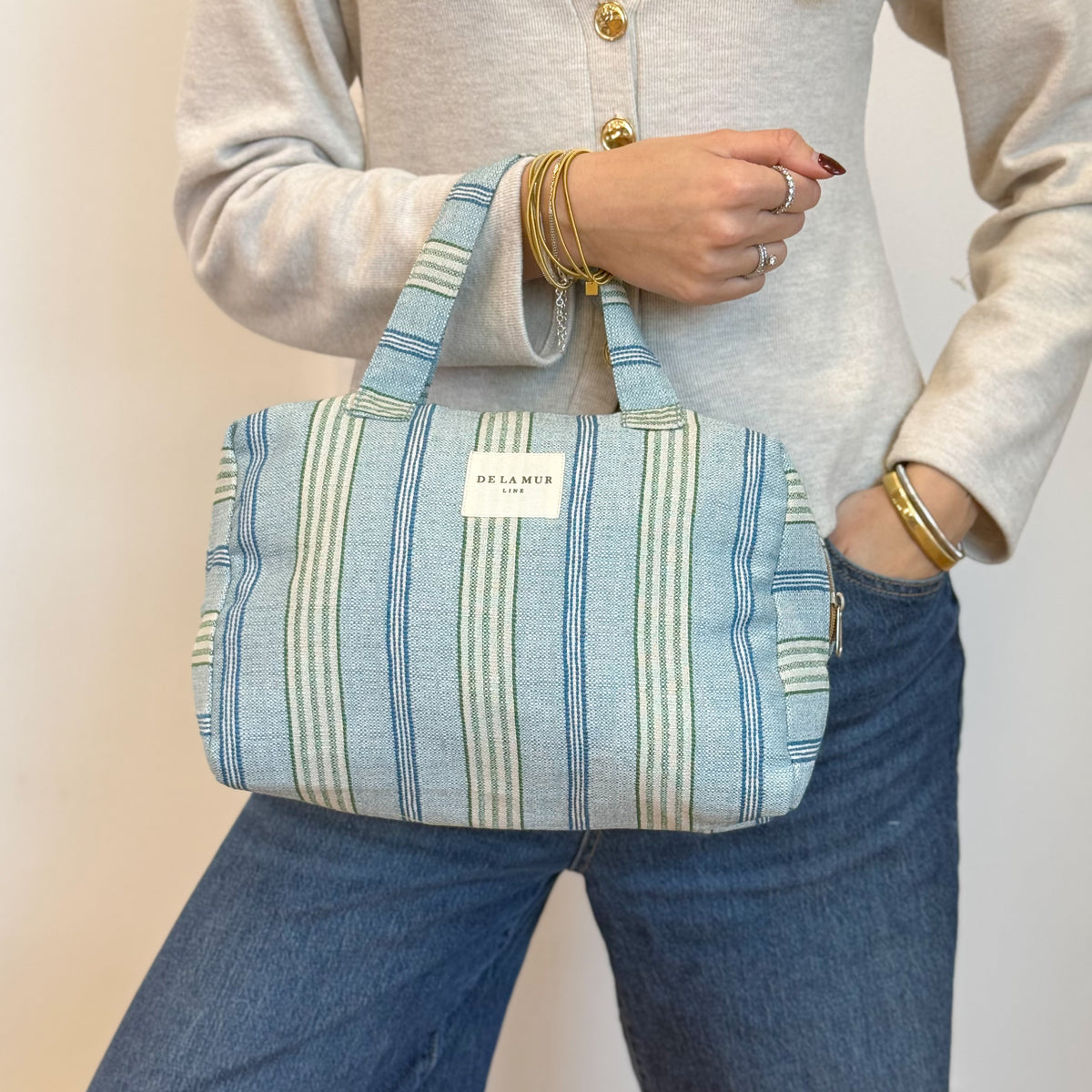 Model carrying the DE LA MUR Cata striped jacquard bag by its top handle