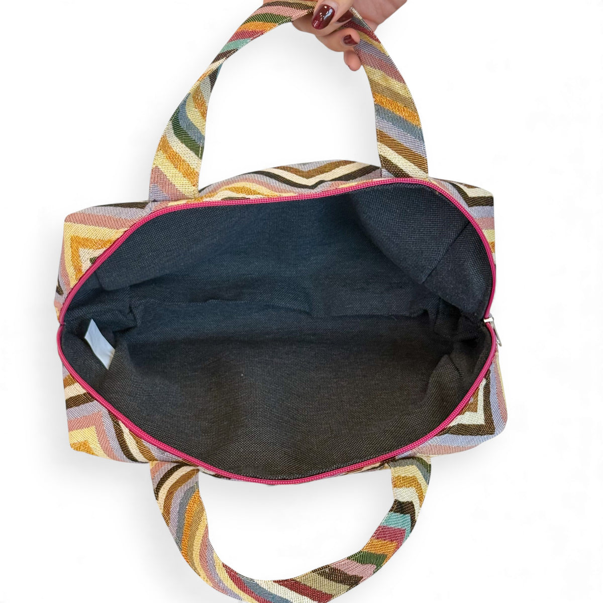 Open DE LA MUR chevron makeup bag showing the dark lined interior and pink zip