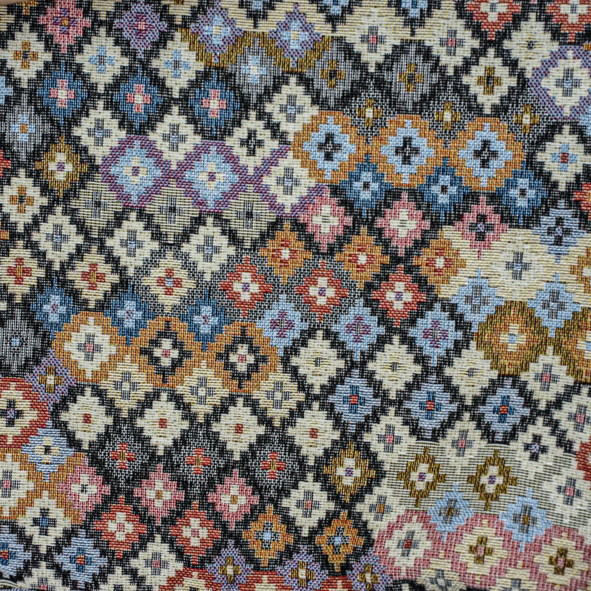 Close-up of the multicolor geometric jacquard weave on the DE LA MUR glasses case
