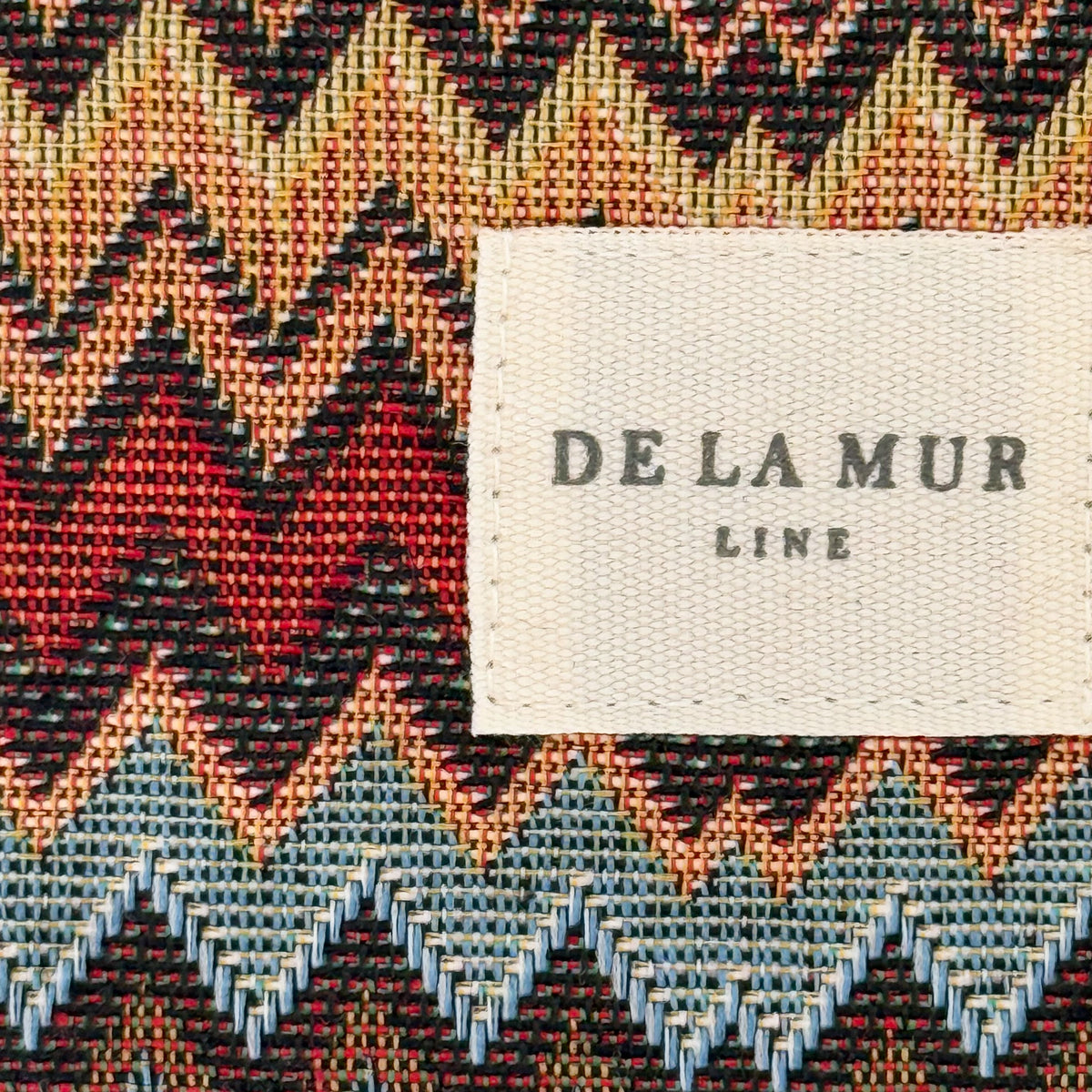 Close-up of the red and blue chevron jacquard fabric and DE LA MUR Line label