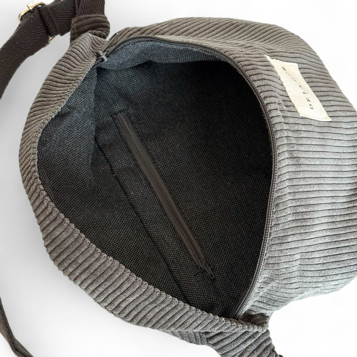 Open DE LA MUR Boni fanny pack showing lined interior with zip pocket