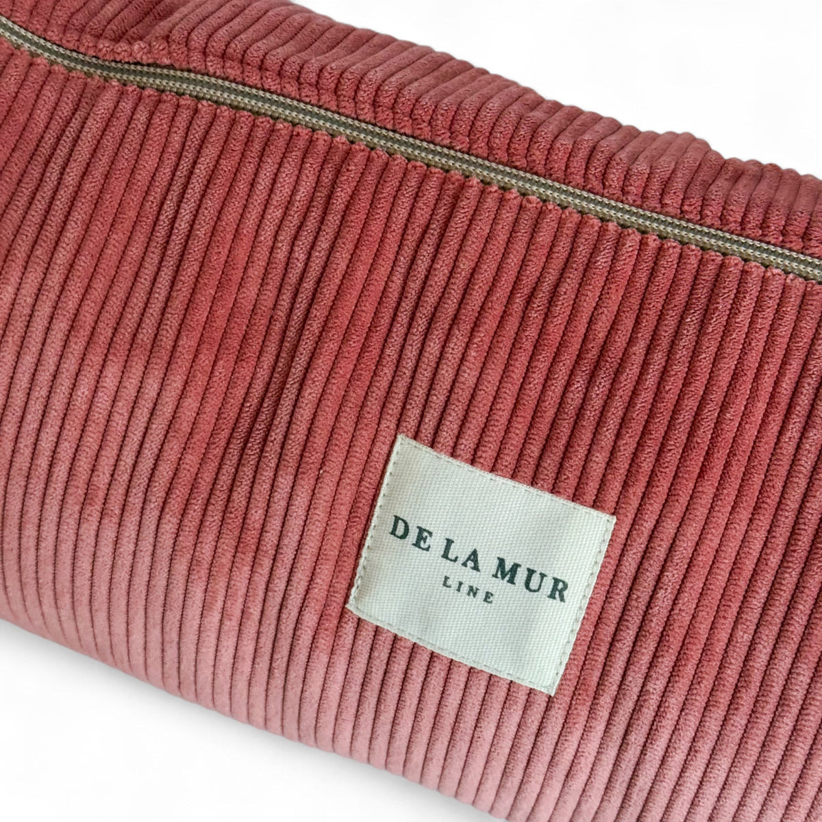 Close-up of coral corduroy texture and DE LA MUR Line label on the yoga mat bag