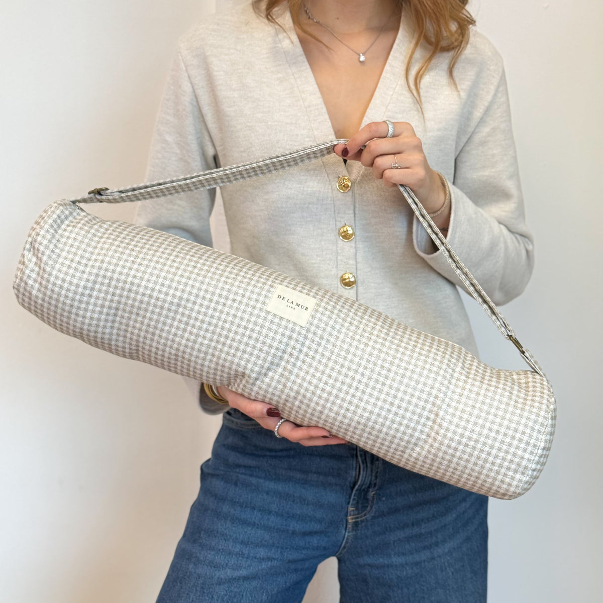 Model holding the DE LA MUR Vison beige gingham jacquard yoga mat bag